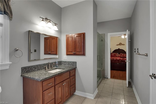 ensuite bathroom featuring tile patterned flooring, a shower stall, baseboards, vanity, and ensuite bath