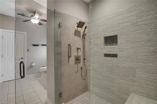 bathroom featuring tile patterned floors, toilet, a ceiling fan, a shower stall, and baseboards