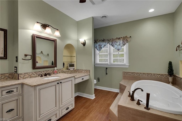 bathroom featuring visible vents, toilet, wood finished floors, a bath, and vanity