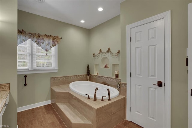 bathroom with recessed lighting, baseboards, wood finished floors, and a bath