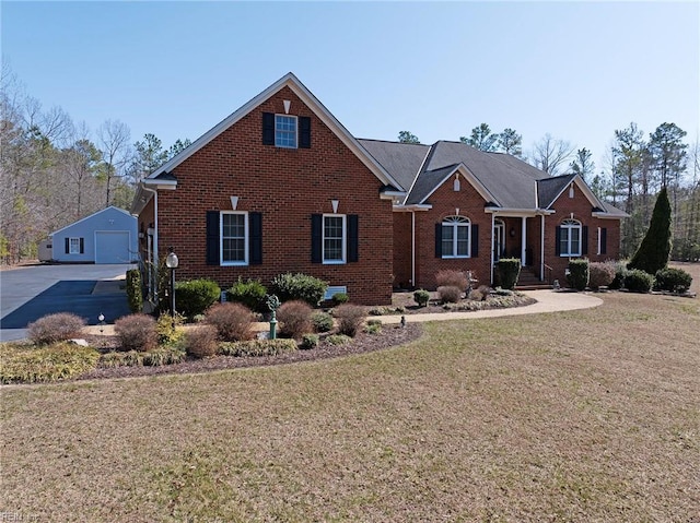 view of front facade featuring a garage, a front yard, an outbuilding, and brick siding