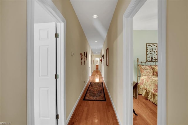 corridor with recessed lighting, wood finished floors, and baseboards