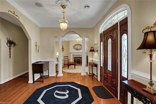 entrance foyer featuring a wealth of natural light, visible vents, wood finished floors, and ornate columns