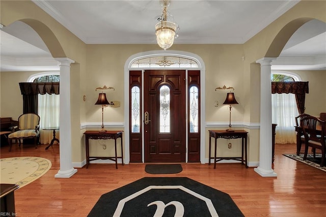 foyer entrance featuring decorative columns, wood finished floors, and plenty of natural light