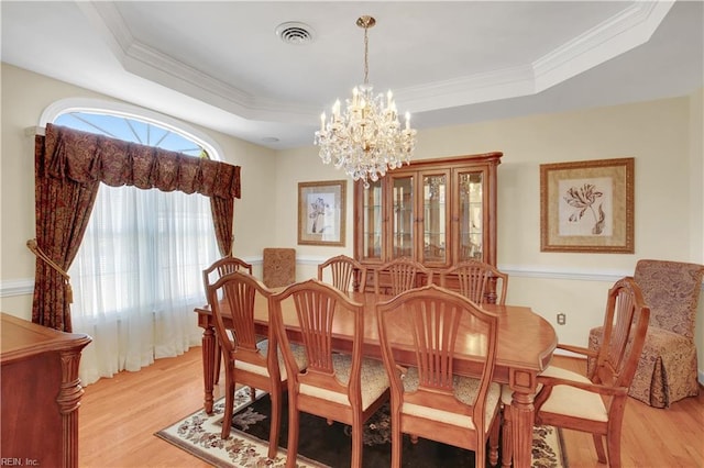 dining area featuring light wood finished floors, a notable chandelier, visible vents, and a tray ceiling