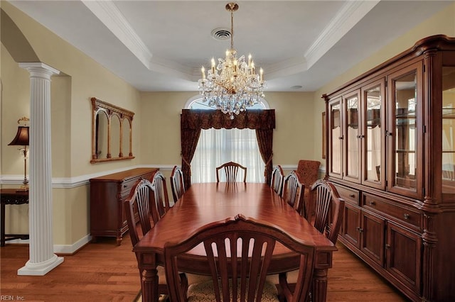 dining room featuring a tray ceiling, wood finished floors, visible vents, and a chandelier