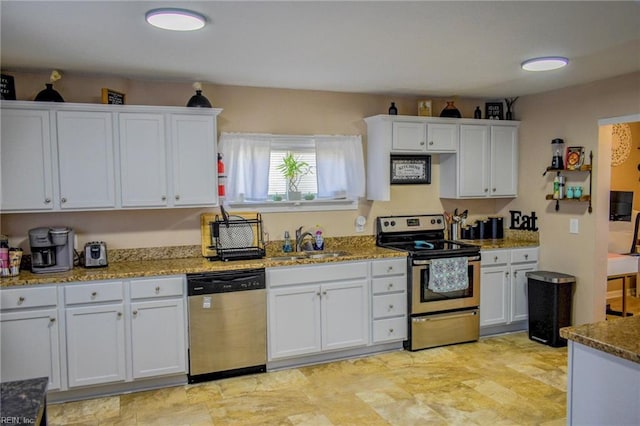 kitchen with white cabinets, light stone counters, stainless steel appliances, and a sink