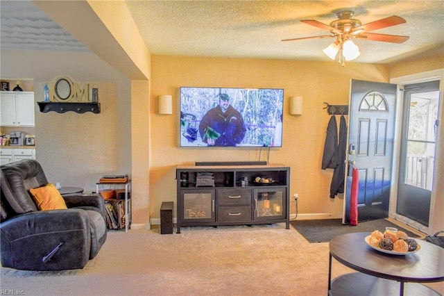 carpeted living room featuring ceiling fan, baseboards, and a textured ceiling