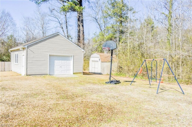 view of yard featuring an outbuilding, a playground, fence, a garage, and driveway