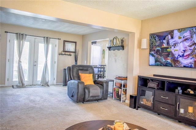 living area with carpet floors, a textured ceiling, and french doors