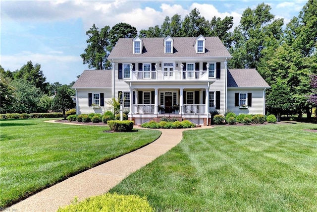 colonial-style house featuring a balcony, covered porch, roof with shingles, and a front yard