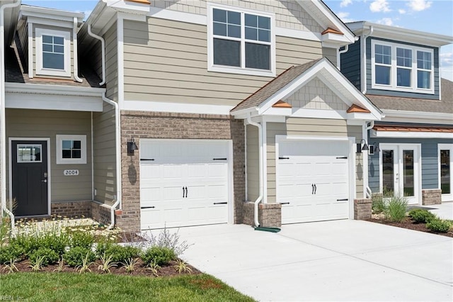 exterior space with a garage, brick siding, a shingled roof, driveway, and french doors