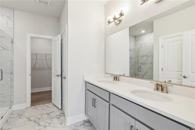 bathroom featuring marble finish floor, a marble finish shower, baseboards, and a sink