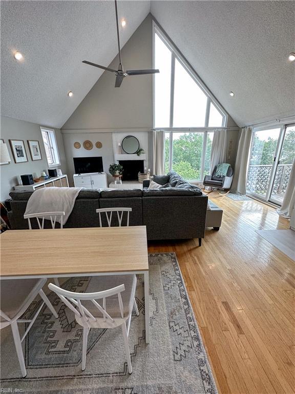 dining area with plenty of natural light, a textured ceiling, high vaulted ceiling, and wood finished floors