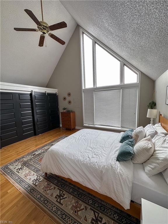 bedroom featuring lofted ceiling, a textured ceiling, wood finished floors, and a ceiling fan