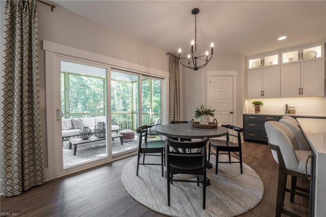 dining area with recessed lighting, dark wood-type flooring, and an inviting chandelier