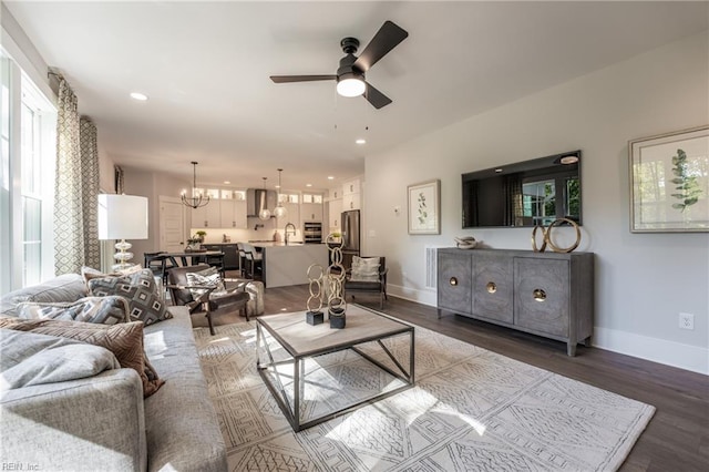 living area featuring baseboards, dark wood-style floors, recessed lighting, and ceiling fan with notable chandelier