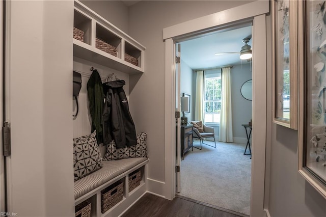 mudroom featuring baseboards, dark colored carpet, ceiling fan, and dark wood-type flooring