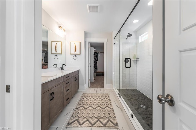 full bath with a sink, a walk in closet, a stall shower, and visible vents