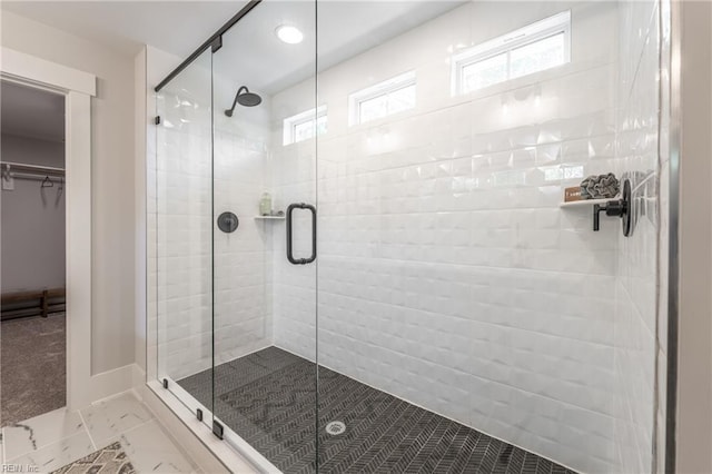 bathroom with baseboards, a wealth of natural light, a spacious closet, and a shower stall