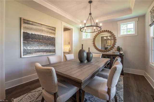 dining area featuring baseboards, a raised ceiling, dark wood-type flooring, and a chandelier