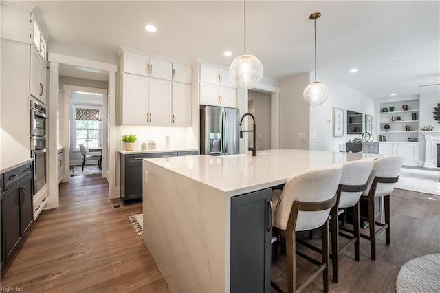 kitchen with dark wood-type flooring, open floor plan, light countertops, and appliances with stainless steel finishes