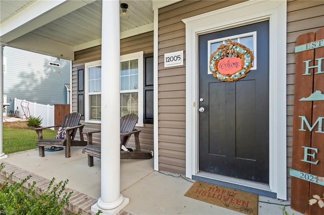 property entrance with a porch and fence