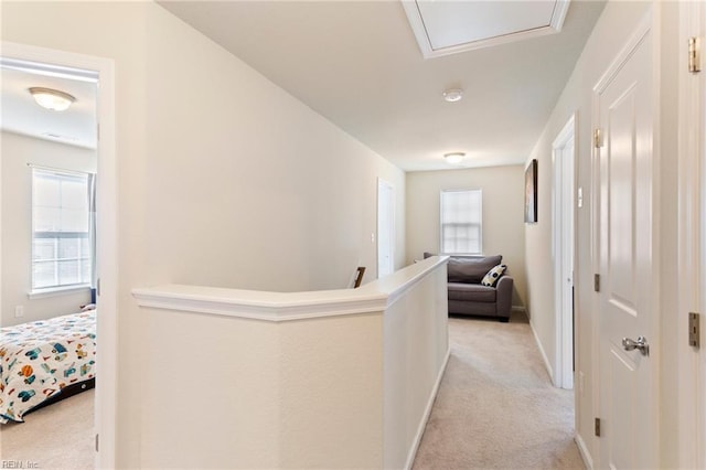 corridor with light carpet, baseboards, and an upstairs landing