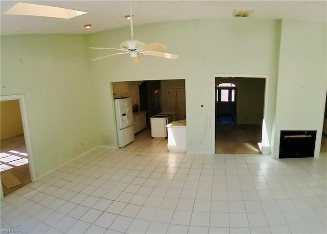 unfurnished living room featuring light tile patterned floors, high vaulted ceiling, a skylight, visible vents, and a ceiling fan