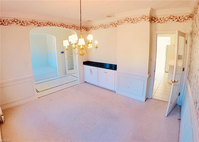 spare room with light carpet, arched walkways, a chandelier, and crown molding