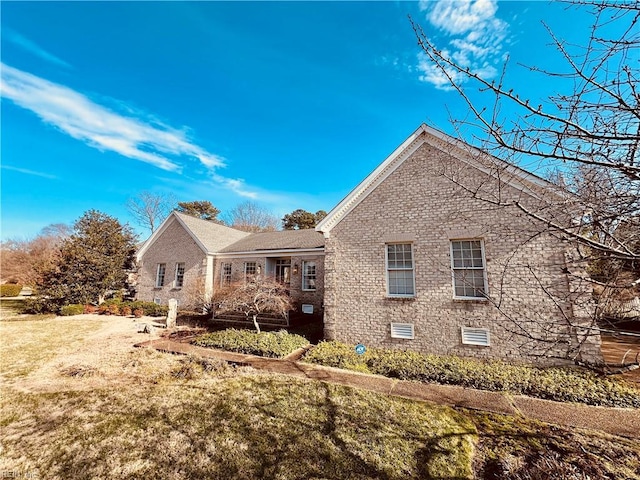 view of front of house with a front yard, crawl space, and brick siding