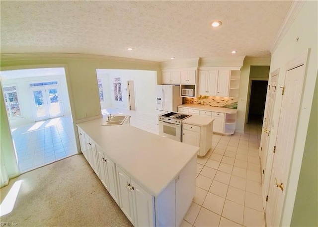 kitchen with white appliances, white cabinets, ornamental molding, a peninsula, and open shelves