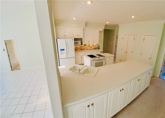 kitchen featuring white appliances, white cabinetry, a sink, and a center island