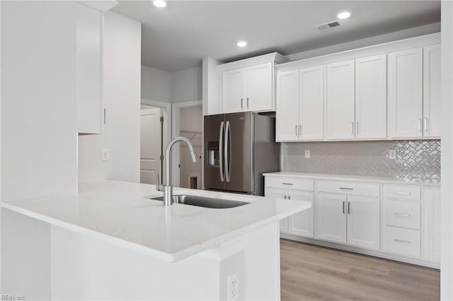 kitchen featuring visible vents, white cabinets, a sink, and stainless steel fridge with ice dispenser