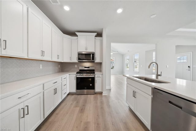 kitchen featuring appliances with stainless steel finishes, a sink, white cabinets, and recessed lighting