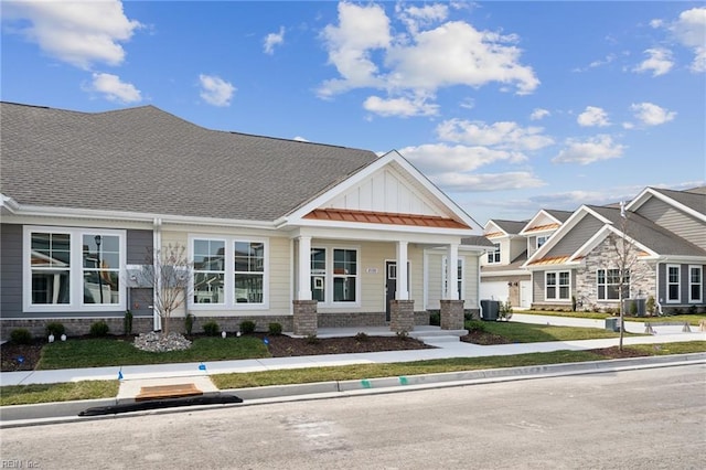 view of front of house with metal roof, a standing seam roof, central AC, board and batten siding, and brick siding