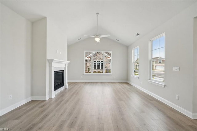 unfurnished living room with baseboards, a ceiling fan, a glass covered fireplace, lofted ceiling, and light wood-type flooring