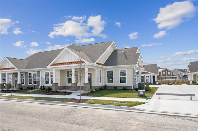 view of front of home featuring brick siding, central AC unit, board and batten siding, a residential view, and a front lawn