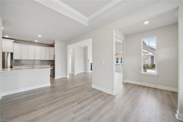 unfurnished living room featuring ornamental molding, recessed lighting, light wood-type flooring, and baseboards