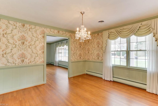 unfurnished dining area with a wainscoted wall, visible vents, ornamental molding, wood finished floors, and wallpapered walls