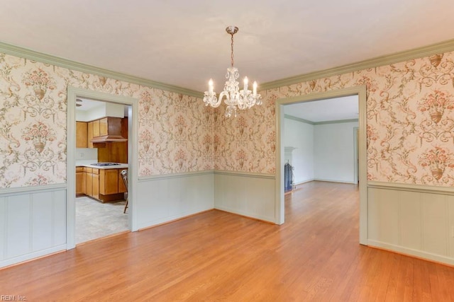 unfurnished dining area featuring light wood-style floors, wainscoting, and wallpapered walls