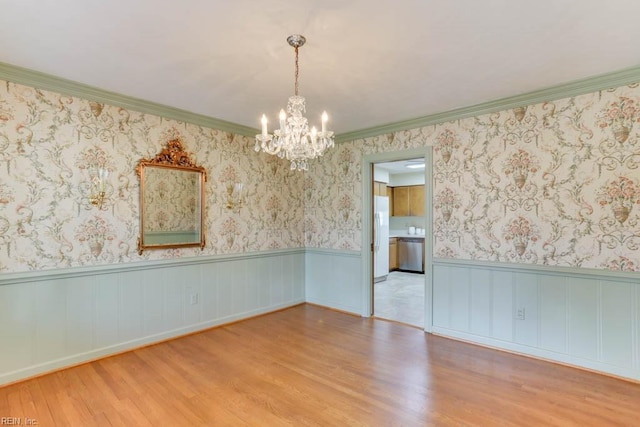 unfurnished room featuring ornamental molding, wood finished floors, wainscoting, and wallpapered walls