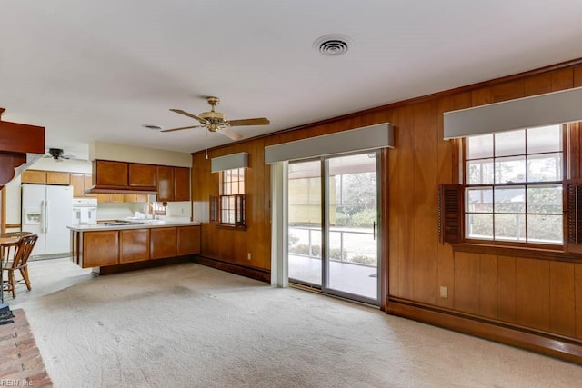 kitchen with brown cabinets, light colored carpet, visible vents, white appliances, and a peninsula