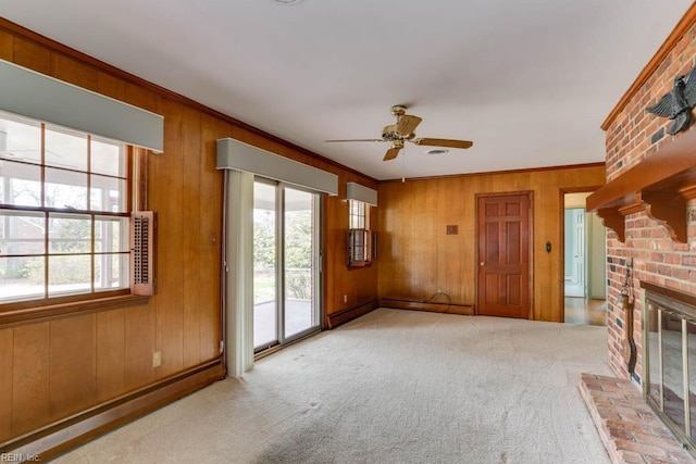 unfurnished living room with a baseboard heating unit, ornamental molding, a fireplace, and carpet flooring