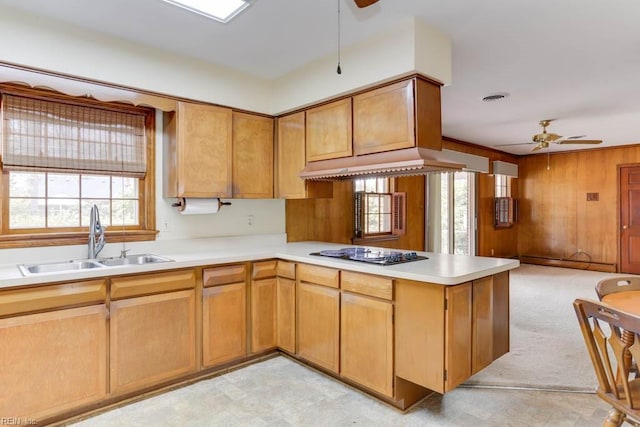 kitchen featuring visible vents, a sink, premium range hood, stovetop, and a peninsula