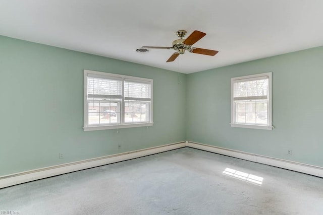 carpeted empty room featuring a baseboard heating unit, ceiling fan, and visible vents