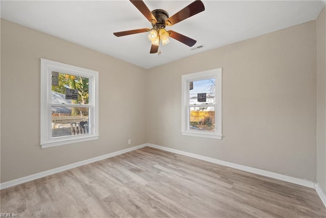 spare room featuring light wood-type flooring, visible vents, and baseboards