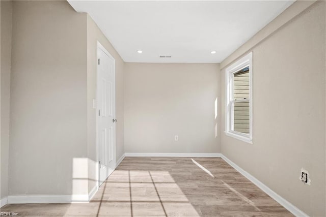 empty room with light wood finished floors, visible vents, baseboards, and recessed lighting