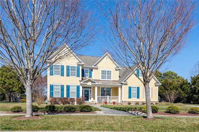 view of front of house featuring covered porch, metal roof, a front lawn, and a standing seam roof