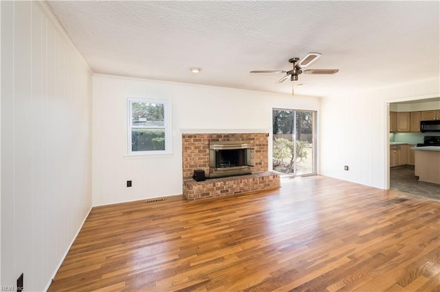 unfurnished living room featuring plenty of natural light, wood finished floors, and a textured ceiling